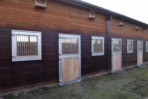 Trzy pary drzwi na padok i cztery okna zamontowane  w stajni dla koni 